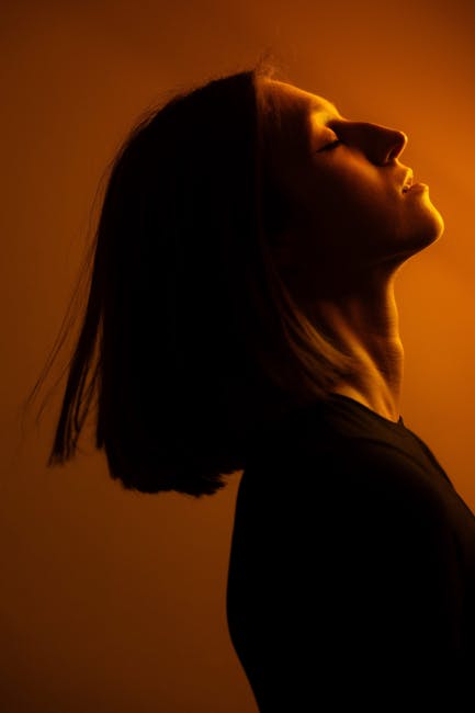 A dramatic side profile portrait of a woman in warm, moody lighting showcasing elegance.