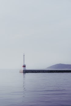 Peaceful sea view with lighthouse in fog creating a serene, calming atmosphere.