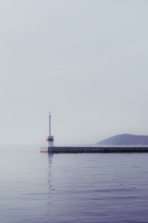 Free Peaceful sea view with lighthouse in fog creating a serene, calming atmosphere. Stock Photo