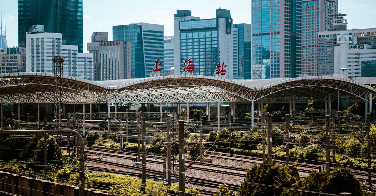 View of Shanghai train station with modern city skyline in background, showcasing vibrant urban architecture.