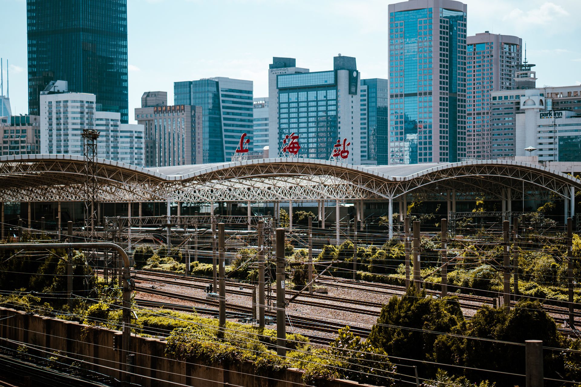 View of Shanghai train station with modern city skyline in background, showcasing vibrant urban architecture.