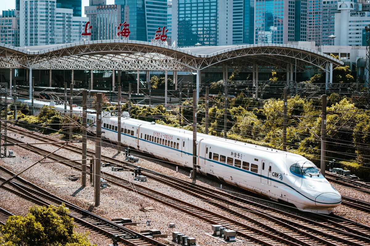 A high-speed train passing through Shanghai Railway Station with the city skyline in the background