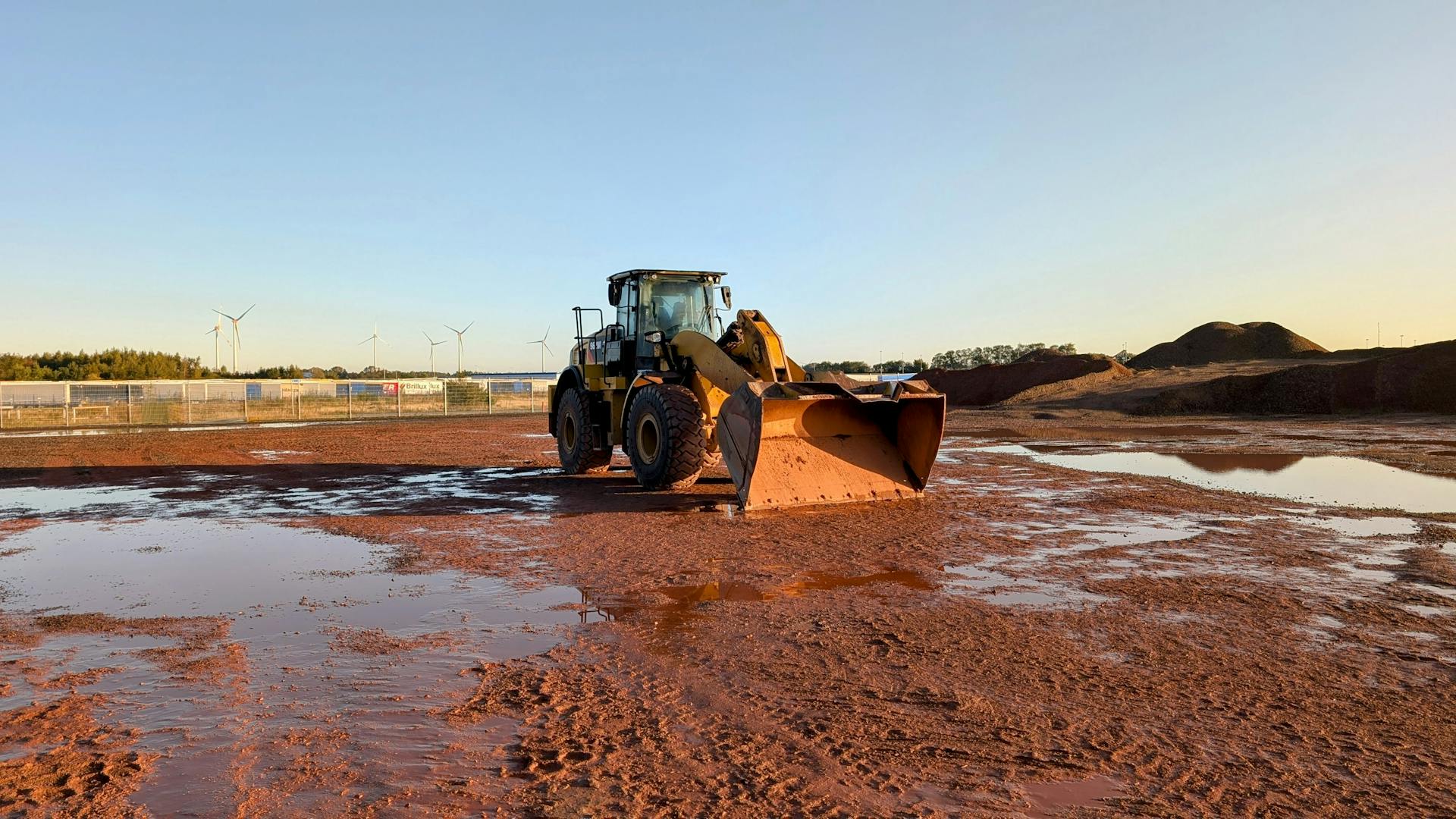 Yellow Bulldozer in Muddy Construction Site at Sunset