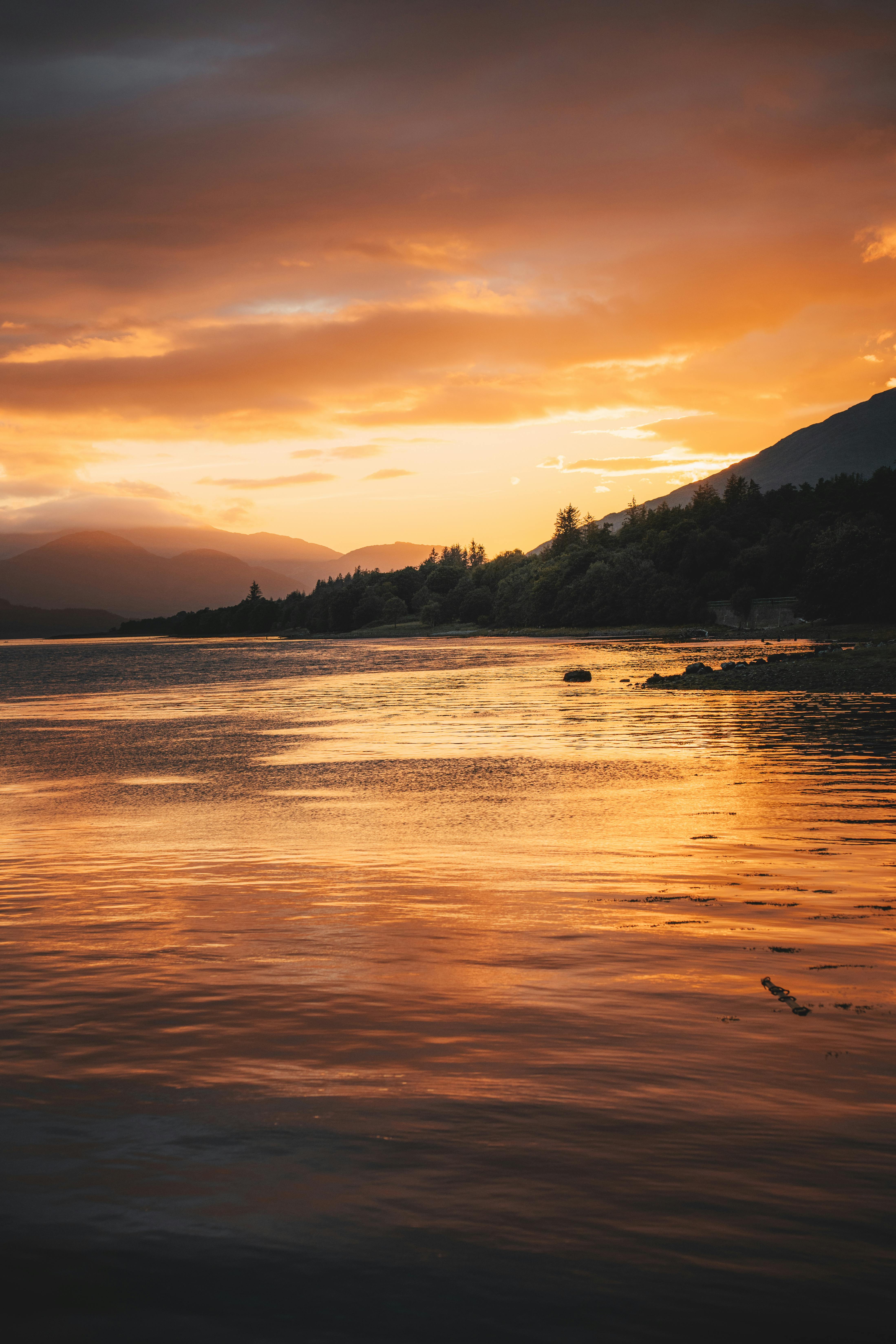 Stunning sunset reflecting over calm waters near Fort William, Scotland, highlighting nature's beauty.
