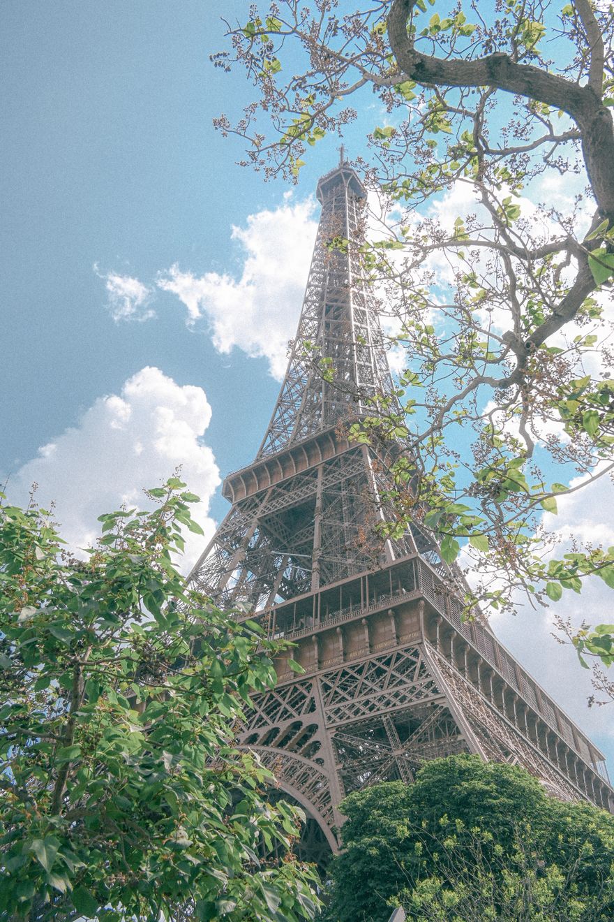Turnul Eiffel din Paris înconjurat de vegetație de primăvară verde și copaci înfloriți