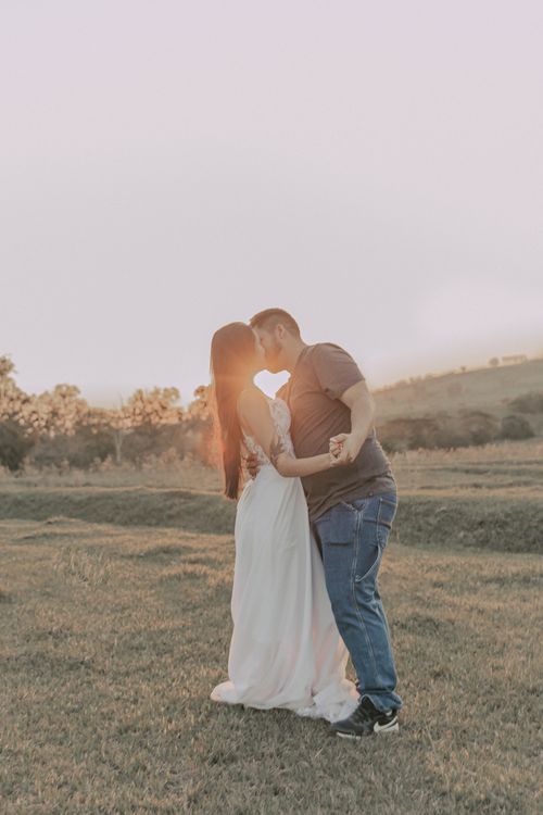 Free A couple sharing a romantic moment outdoors at sunset, embracing in a serene field. Stock Photo