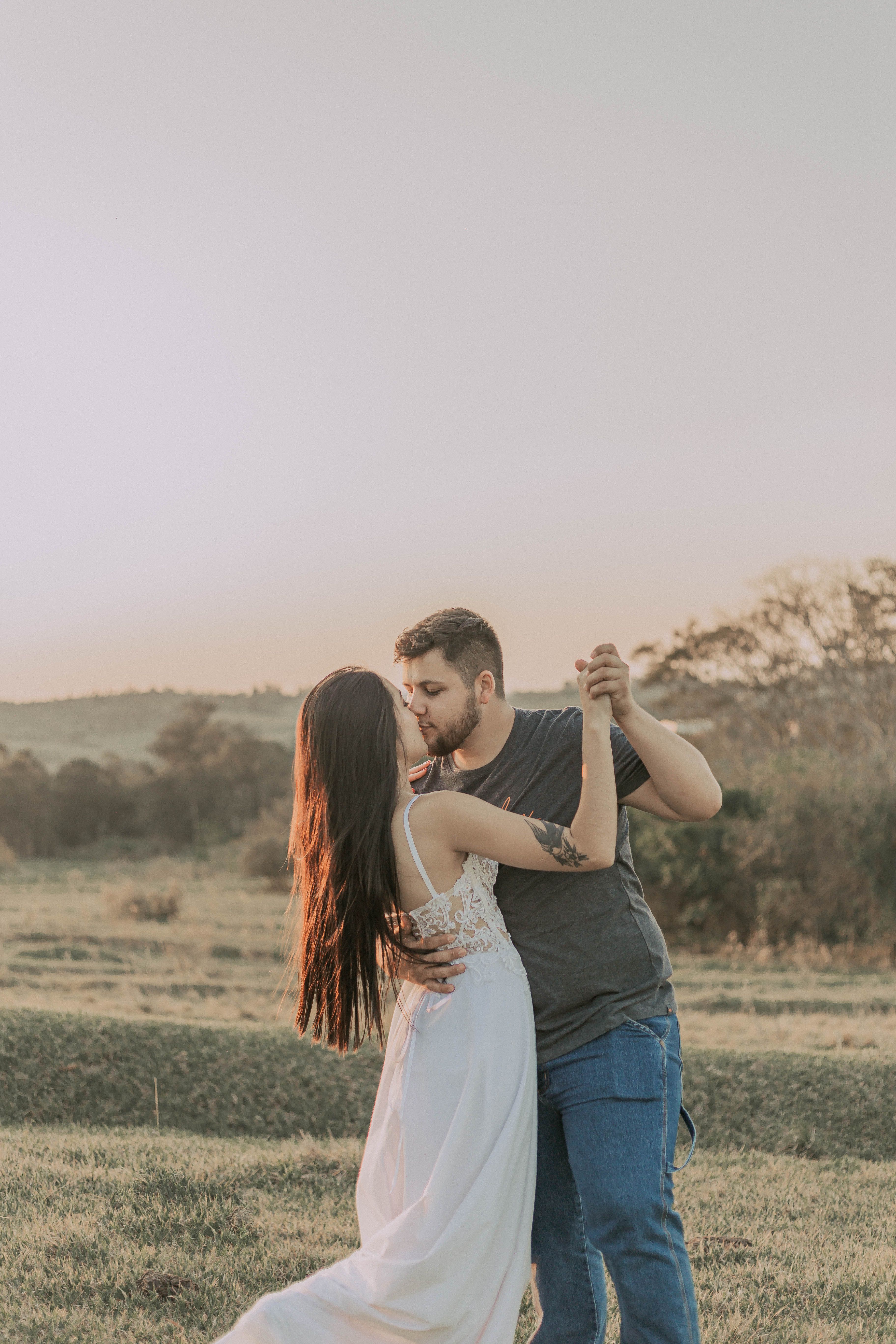 A couple shares a romantic embrace in a scenic nature setting during sunset.