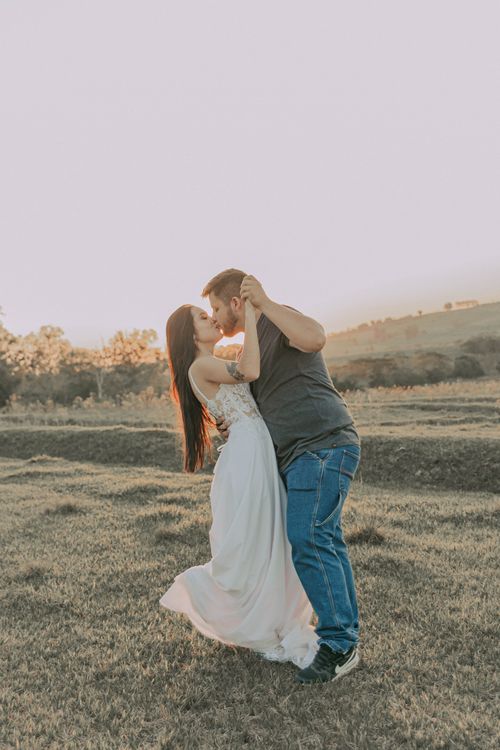 Free Couple embracing in a field during a sunset photo session, showcasing love and nature. Stock Photo