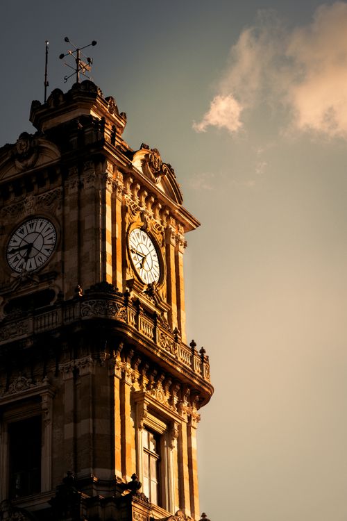 Free Elegant example of Ottoman architecture, Dolmabahçe Clock Tower illuminated during sunset in Istanbul, Turkey. Stock Photo