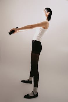 Woman in workout attire doing exercises with dumbbells indoors.