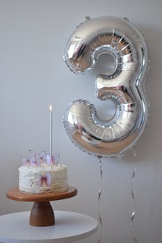 Elegant third birthday setup with butterfly cake and large numeral balloon.