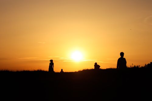 Free Silhouettes against a sunset, creating a serene and warm atmosphere with vibrant colors. Stock Photo
