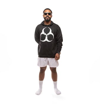 A confident man wearing a black hoodie and white shorts poses in a studio setting.