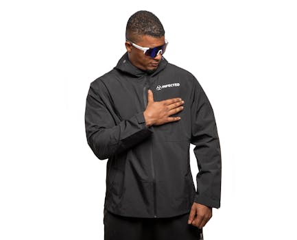 Stylish man in black sports jacket with sunglasses, showcasing modern sportswear.