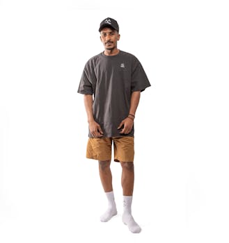 A man wearing an oversized t-shirt, cap, shorts, and socks standing against a white background.