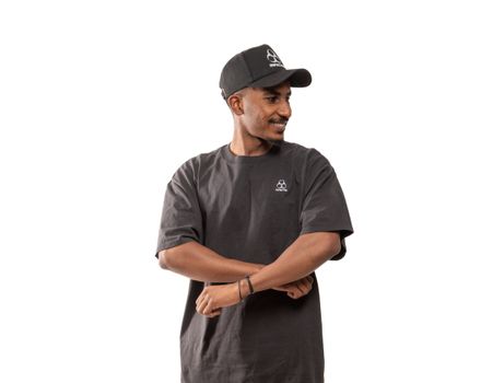 Smiling man in a black T-shirt and cap with folded arms.