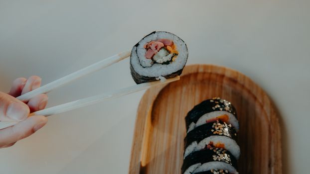 Close-up of sushi with chopsticks on wooden tray. Perfect for food and lifestyle themes.