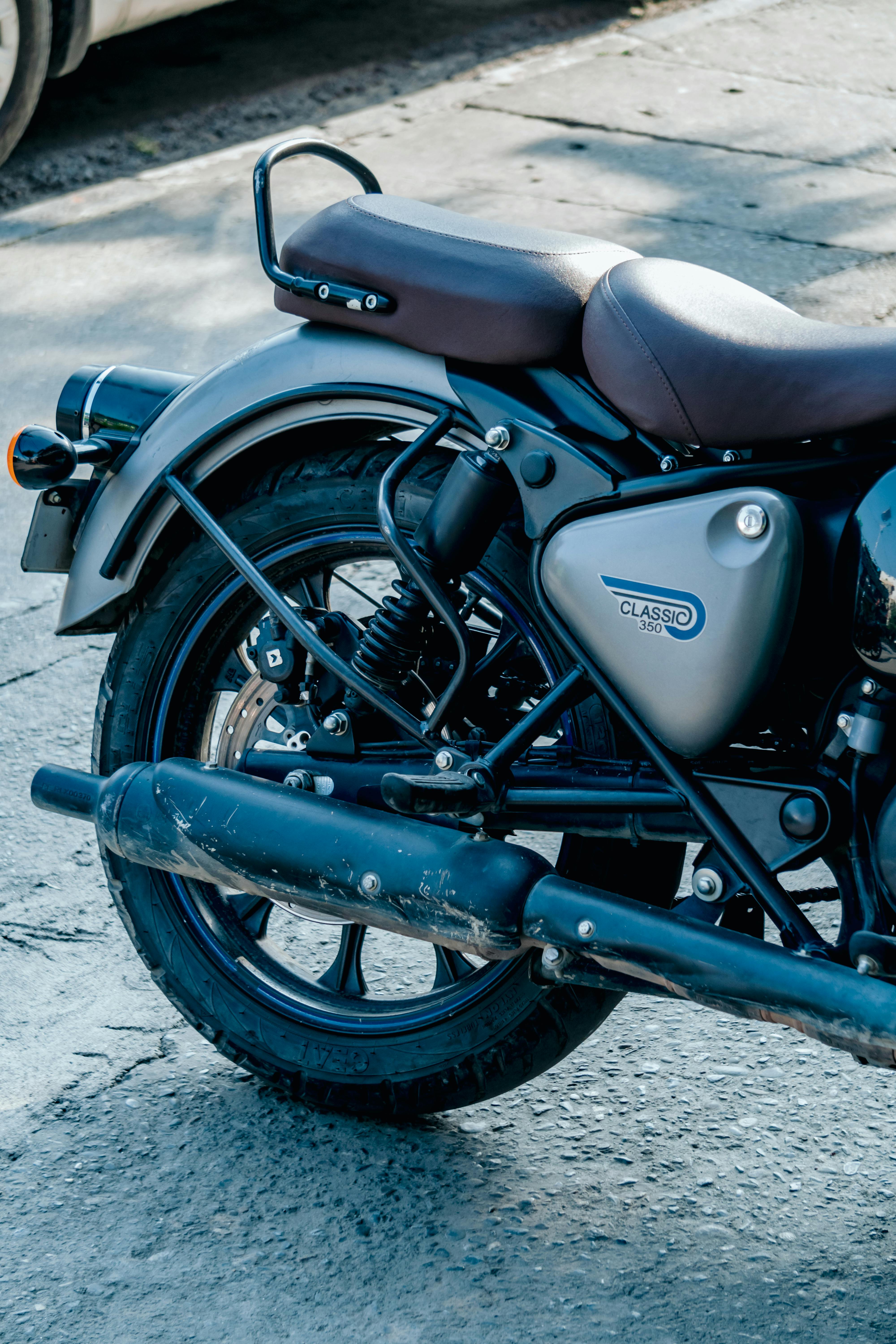 Rear view of a classic motorcycle parked on an urban street, highlighting its retro design.
