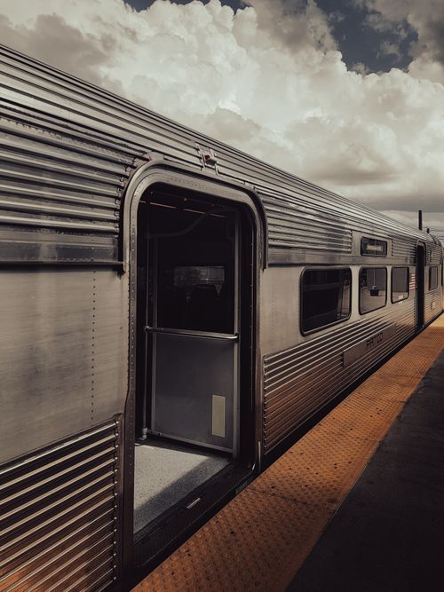 Free A metallic train waits at an open platform under a cloudy sky, capturing travel intrigue. Stock Photo