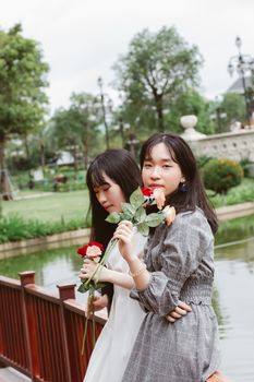 两名年轻女子拿着玫瑰，在公园度过了一天，展现了友谊与休闲
