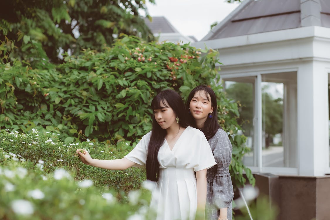 Two Women Standing Beside Flowering Plants