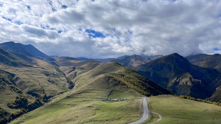 Paysage de montagne à couper le souffle dans le Caucase avec une route sinueuse et un ciel nuageux.