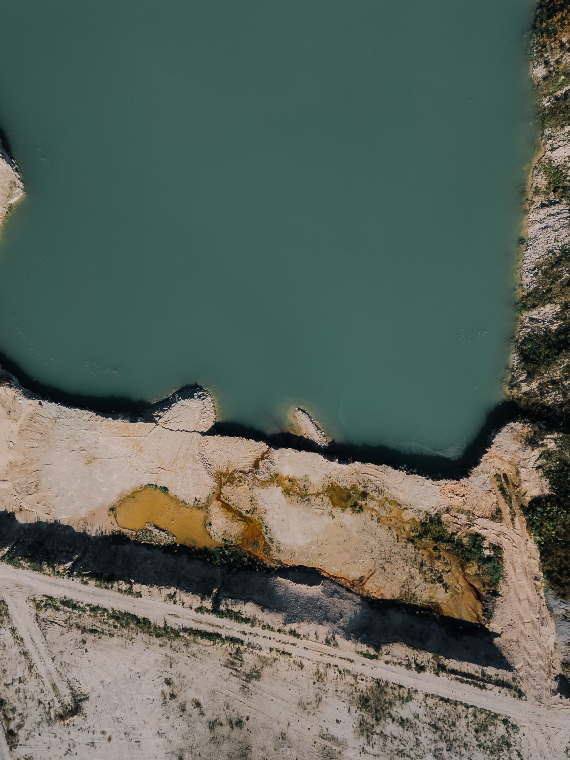 Stunning aerial view of a quarry with turquoise water in Latvia, showcasing nature's contrast.