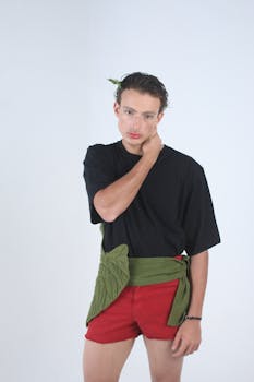 Stylish portrait of a young adult in modern fashion with a relaxed pose against a plain backdrop.