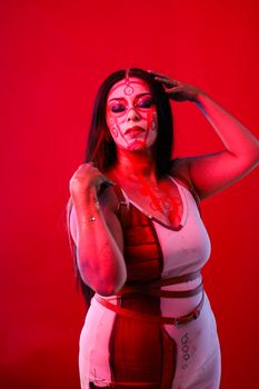 A striking portrait of a woman with intricate face paint against a vivid red backdrop.