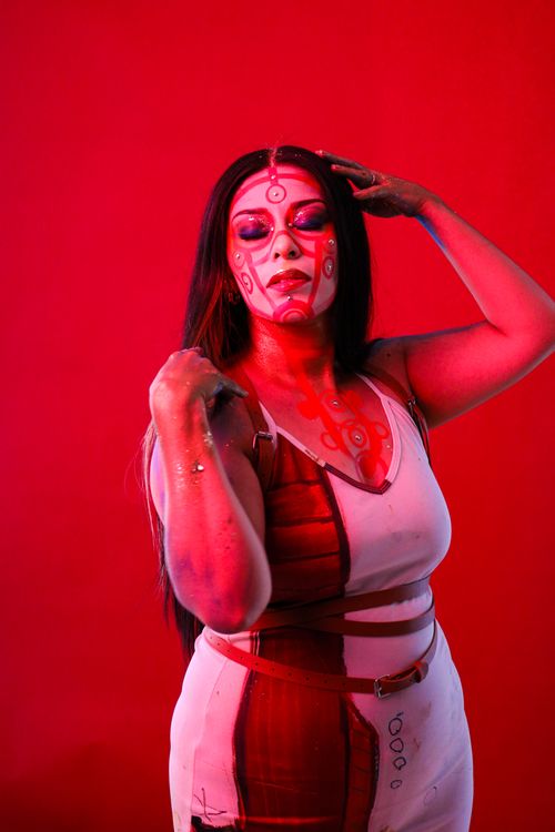 Free A striking portrait of a woman with intricate face paint against a vivid red backdrop. Stock Photo