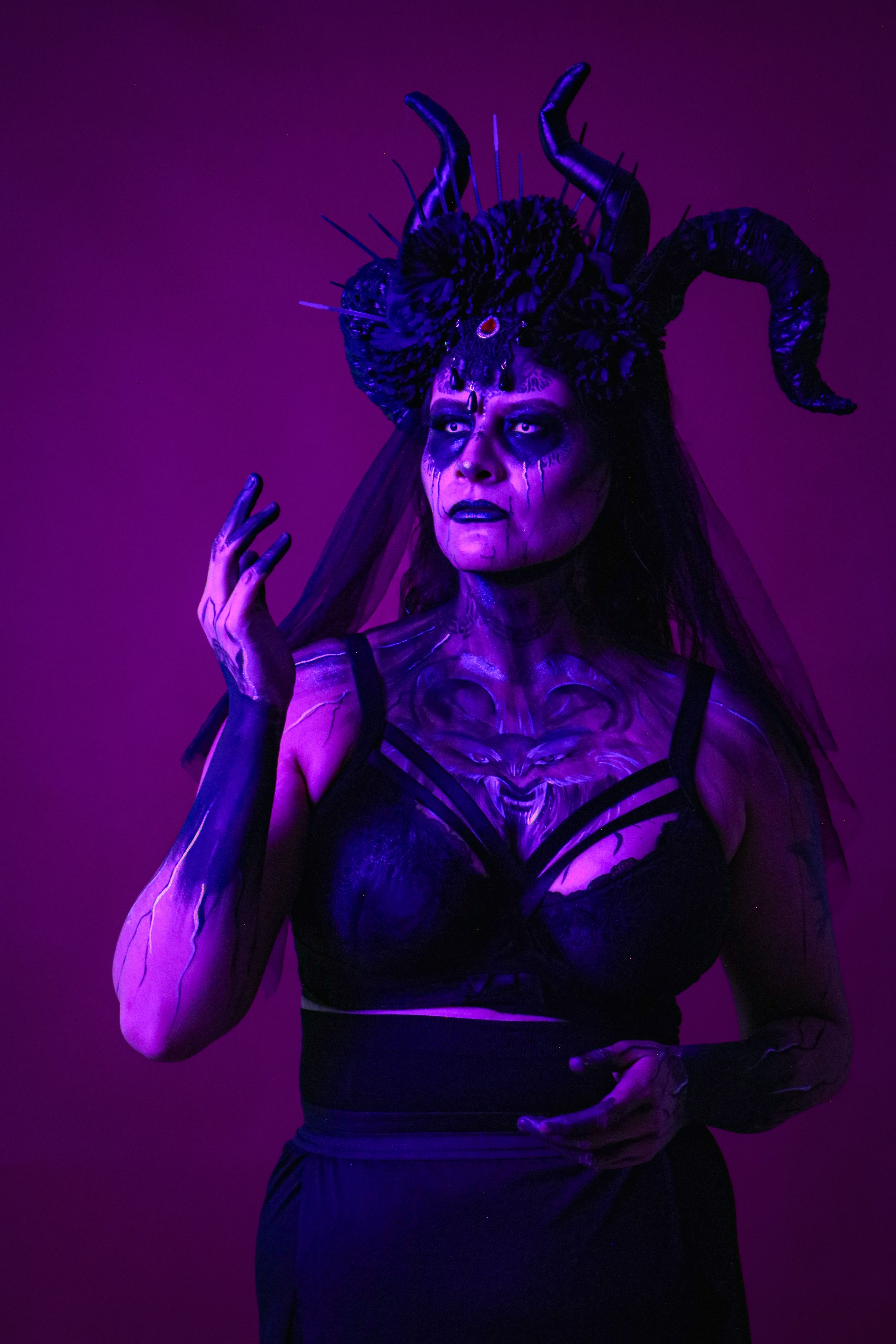 Dark, mysterious portrait of a woman in elaborate costume with vivid purple lighting.