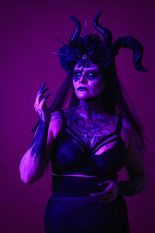Free Dark, mysterious portrait of a woman in elaborate costume with vivid purple lighting. Stock Photo