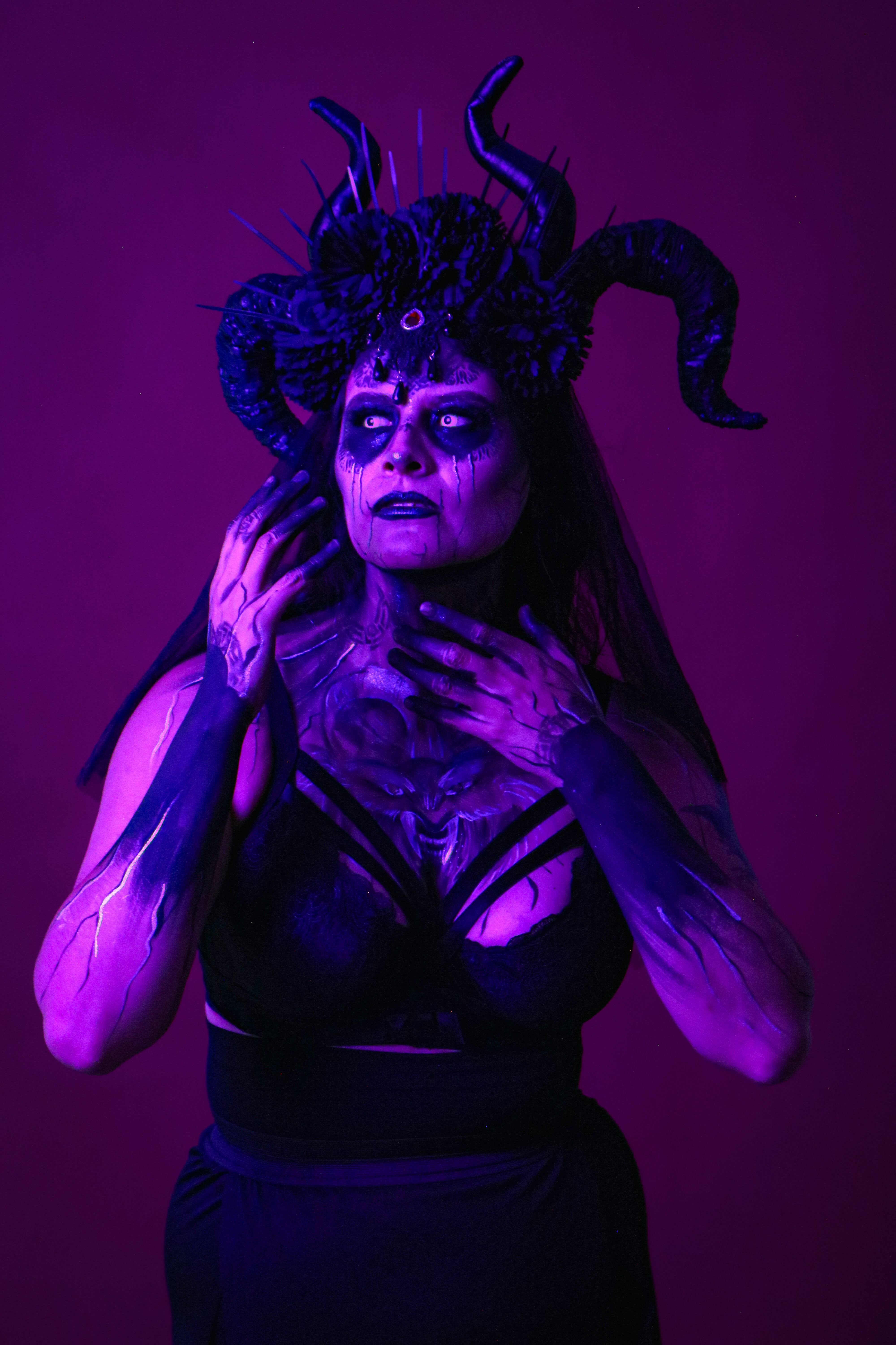 A woman in a creative fantasy costume with dark and vibrant lighting.