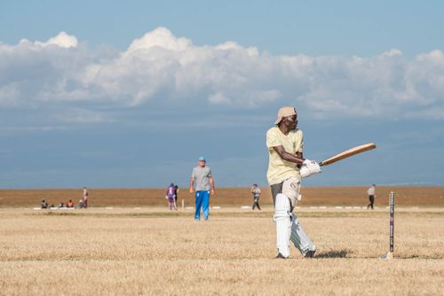 Free A player batting in a cricket match in an open field with a blue sky, capturing the essence of outdoor sports. Stock Photo