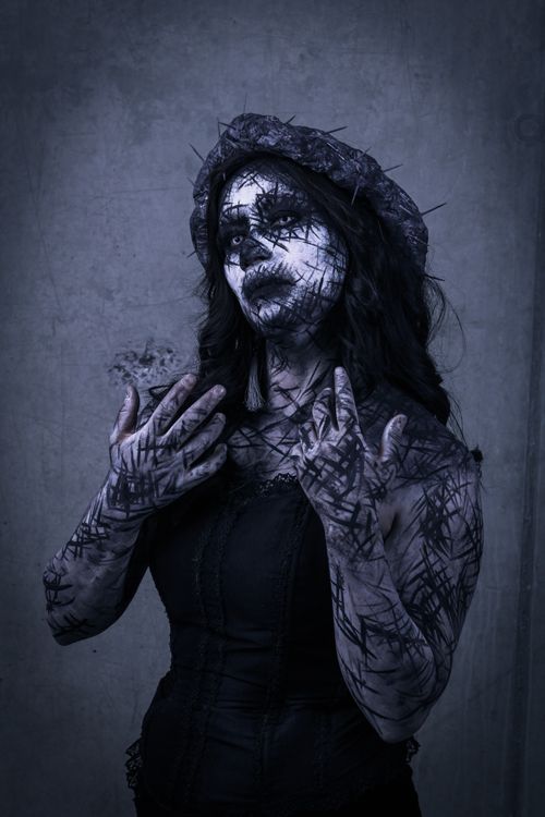 Free A dark, artistic portrait of a woman with dramatic face paint and expressive pose. Stock Photo