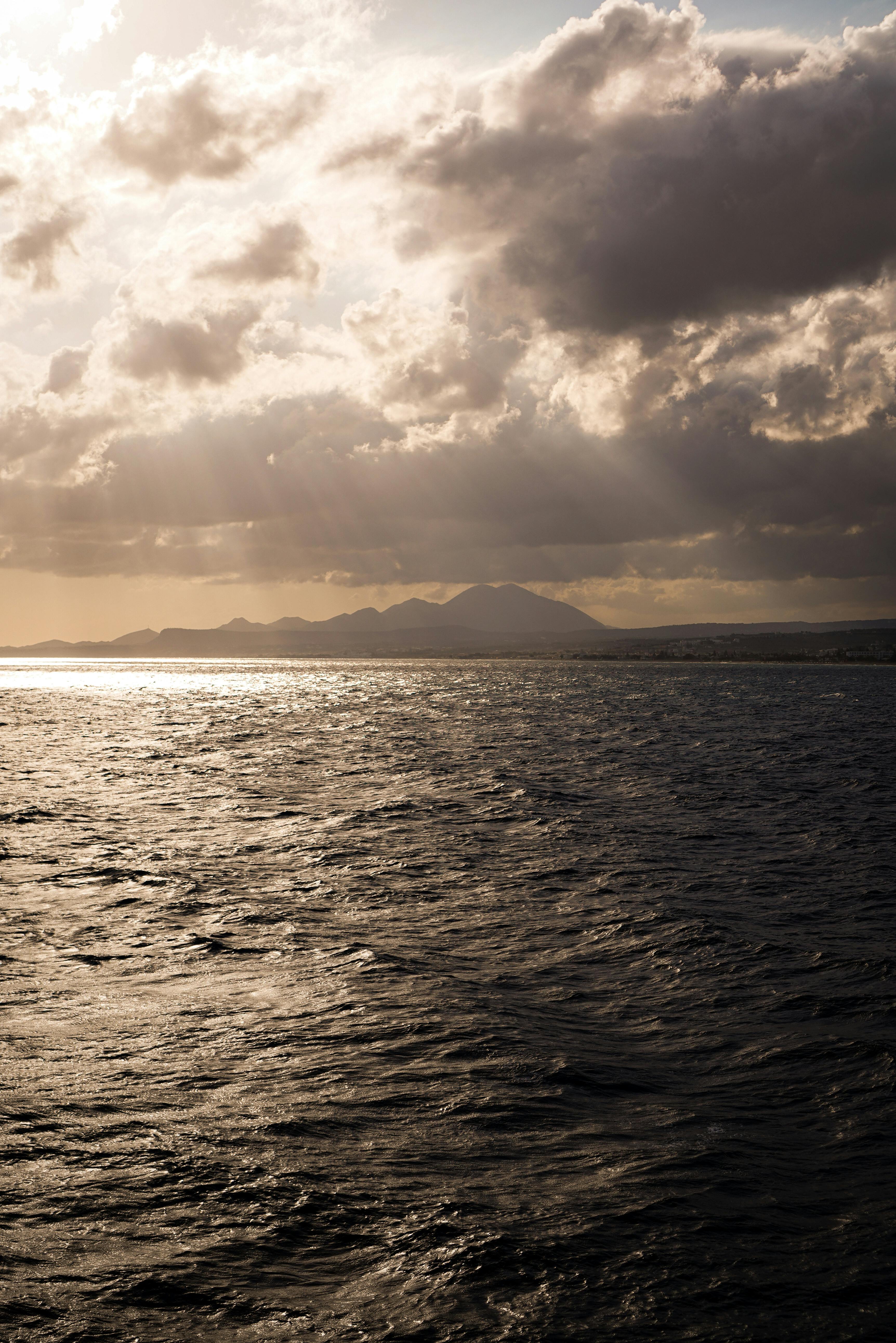 Gorgeous seascape featuring dramatic clouds and sunset rays over the ocean waves.