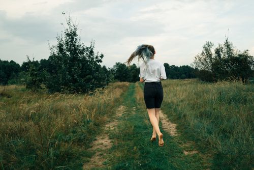 Free A woman joyfully runs through a lush green field, embracing the outdoors. Stock Photo