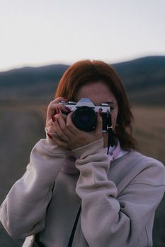 Young woman photographing outdoors with vintage camera.