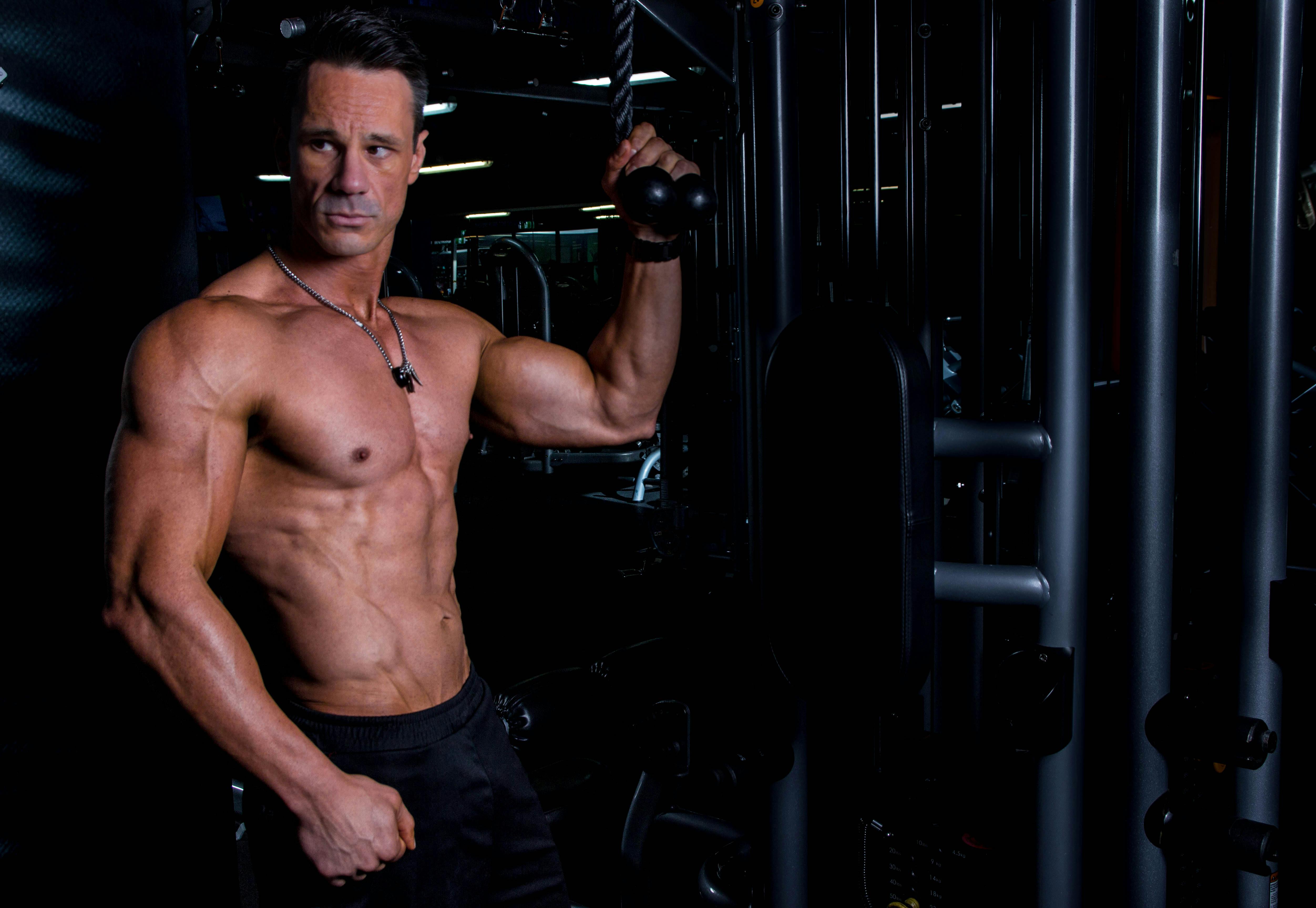 Athletic male exercising indoors, showcasing strong physique in a gym environment.