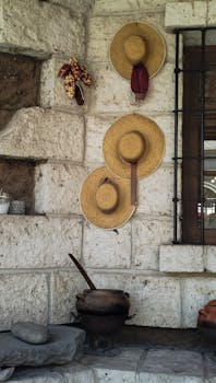 Traditional rustic decor with straw hats and stone wall, evoking a simple lifestyle.