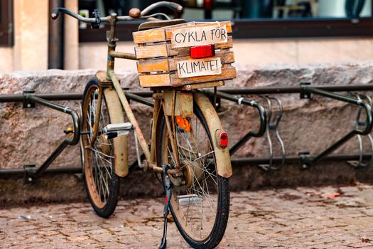 Rustic bicycle with 'Cykla för Klimatet' sign parked in Jönköping, Sweden.