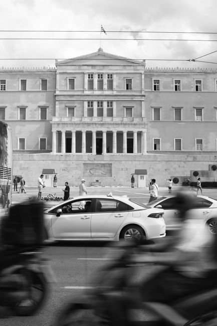 Monochrome image of Athens Parliament with motion blur and cars.
