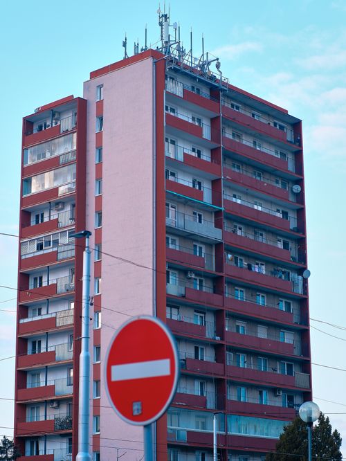 Free Tall apartment building with communication antennas and a no entry sign. Stock Photo