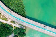 无人机航拍下，绿松石般的水域上横跨着一座公路桥，四周环绕着郁郁葱葱的绿植