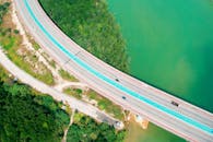 航拍照片中，一条高速公路蜿蜒穿过郁郁葱葱的绿色河流弯道，展现了自然与基础设施的交融