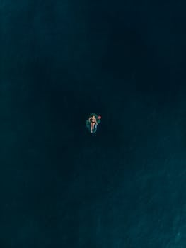 广阔的蓝色海洋中，一个单身女人在充气浮标上放松，营造出宁静祥和的景象