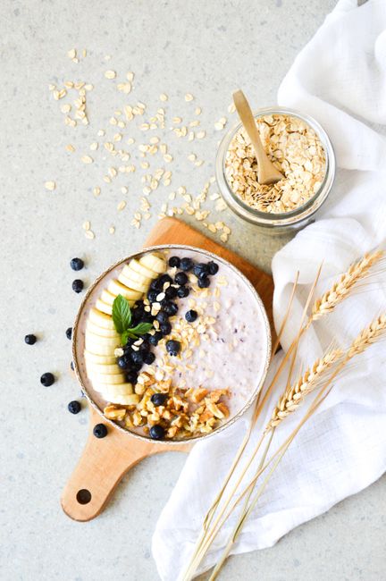 Appetizing breakfast bowl with oats, banana, blueberries, and walnuts on a light background.