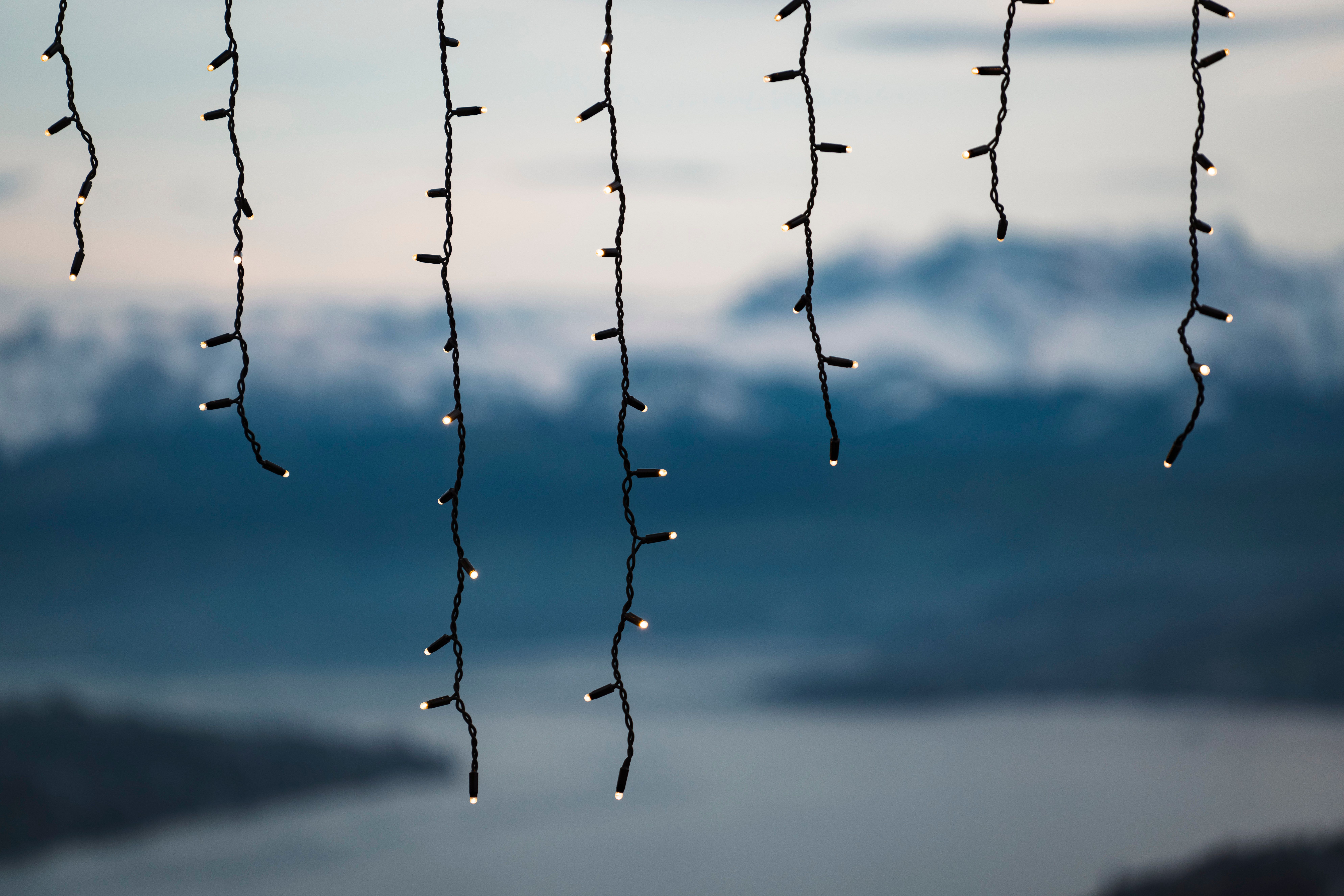Enchanting fairy lights hanging against a serene mountain backdrop, perfect for festive and tranquil settings.