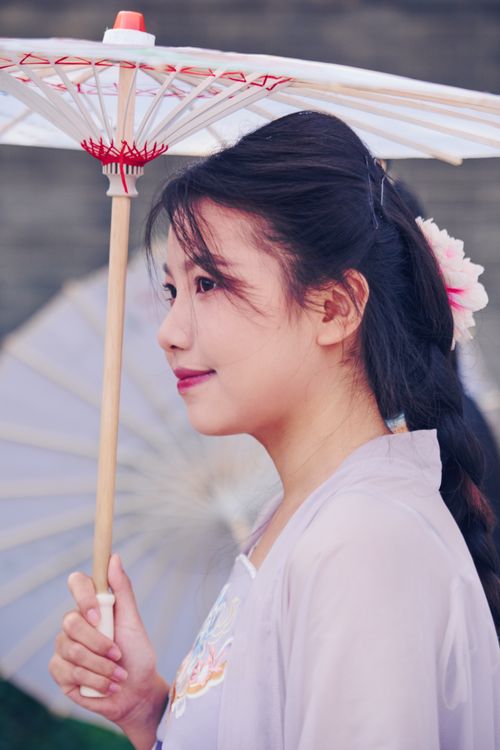 Free Side profile of a woman holding a traditional parasol, wearing soft pastel colors. Stock Photo