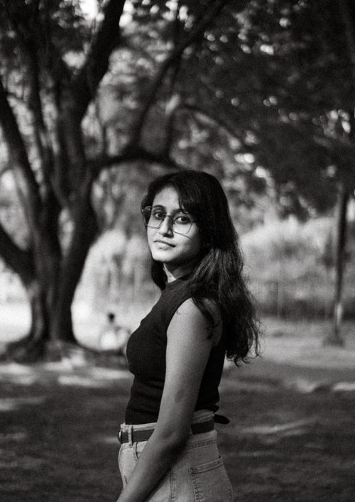 Free Elegant black and white portrait of a young woman standing in a serene outdoor park. Stock Photo